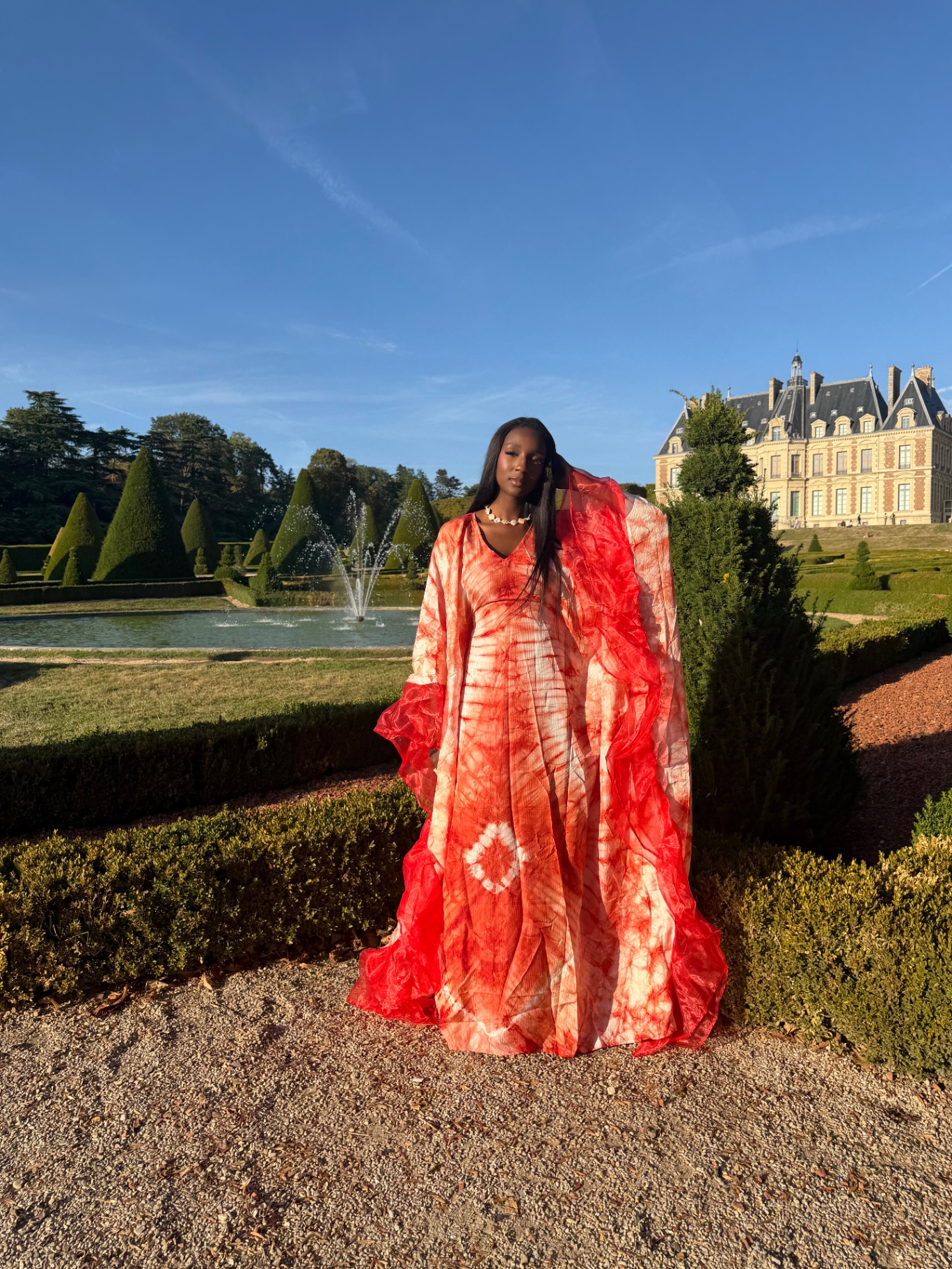 Robe longue rouge et crème devant un château