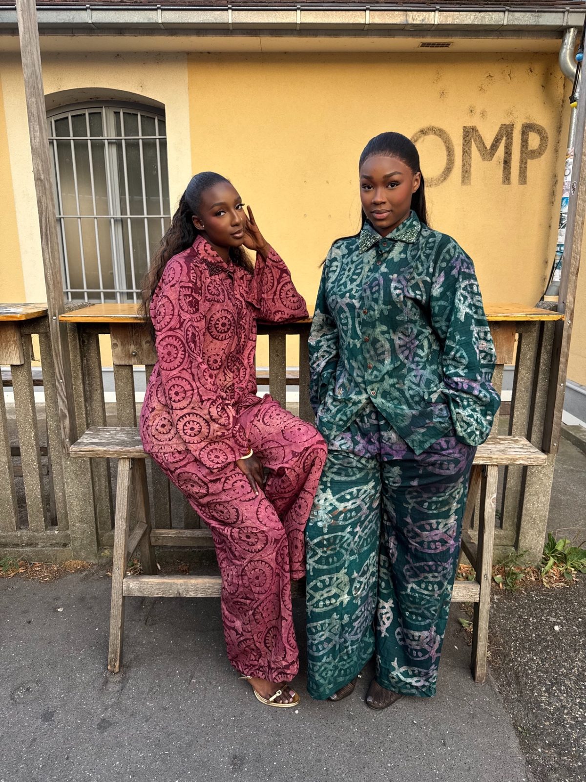 Deux femmes assises portant des ensembles Oumy’s House à motifs violets et verts